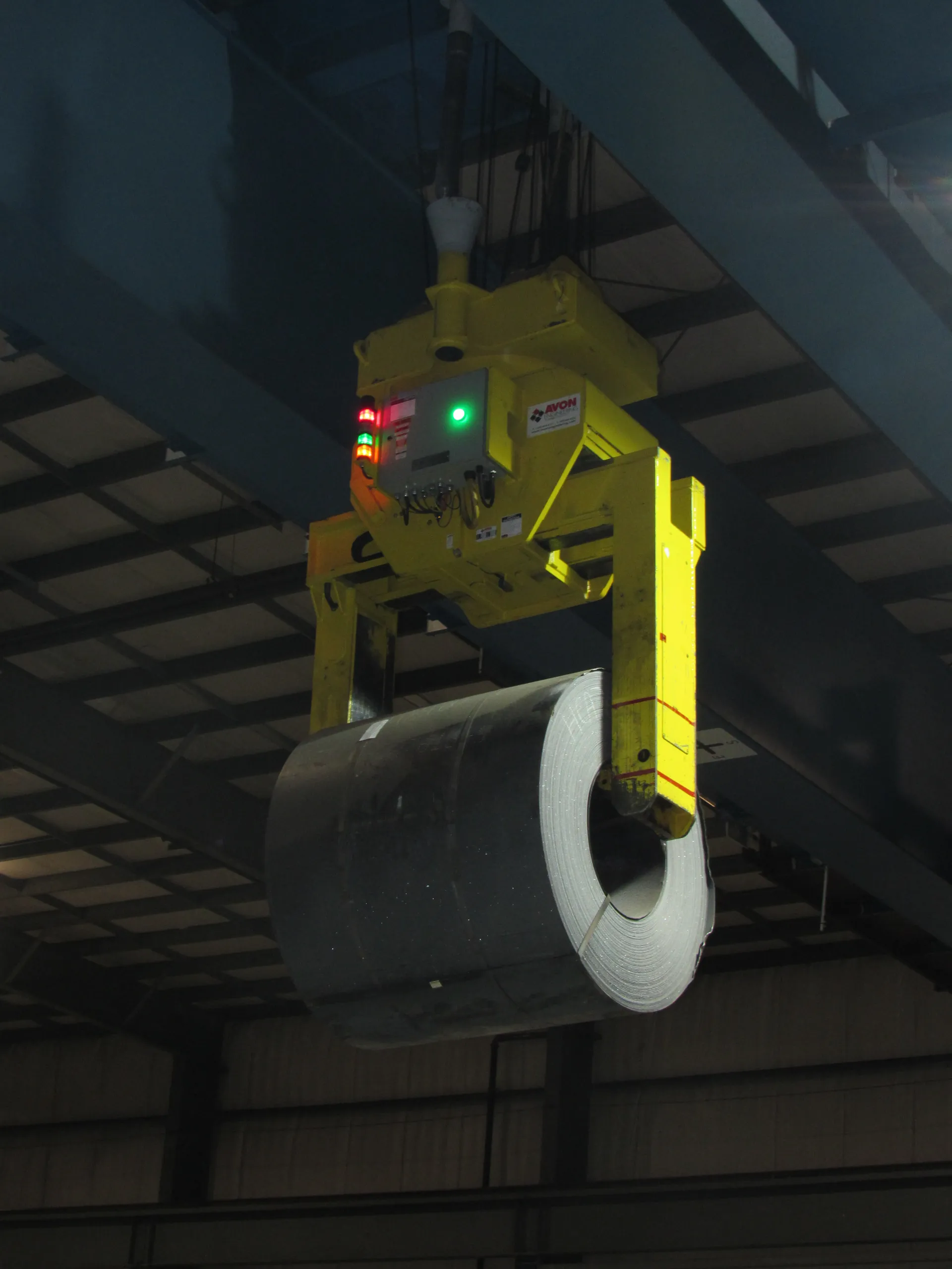 Crane moving a coil between storage and processing areas