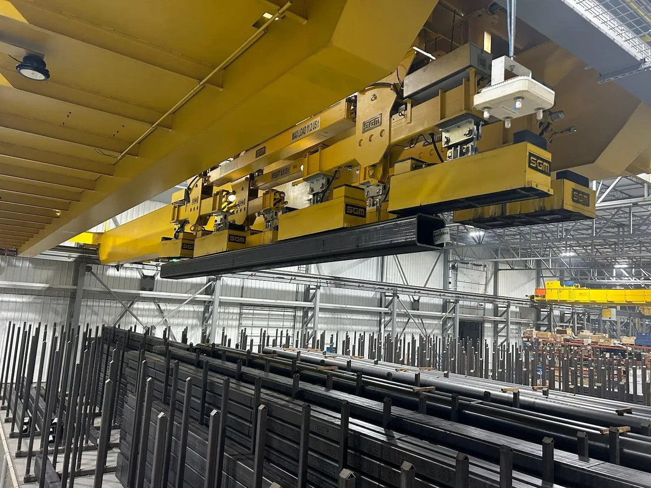 Pipe and tube stored in racks beside a crane magnet